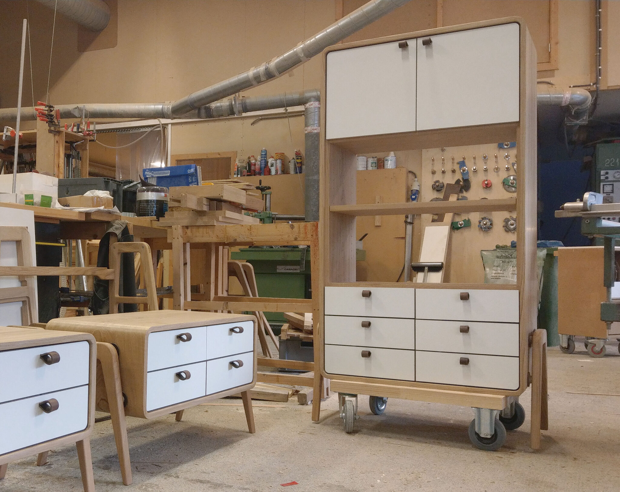 A workshop shot of a large, custom-made oak dresser with white fronts, featuring 2 doors at the top, 2 open compartments in the middle, and 6 drawers at the bottom, ready for delivery. nordlys møbler: HANDMADE - SCANDINAVIAN - FURNITURE from Norwegian oak 