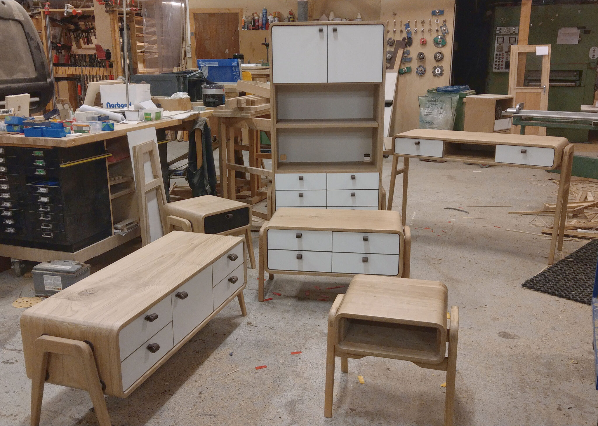 A busy workshop scene showcasing the variety of our craft, displaying five different custom oak furniture pieces with black or white fronts. nordlys møbler: HANDMADE - SCANDINAVIAN - FURNITURE from Norwegian oak